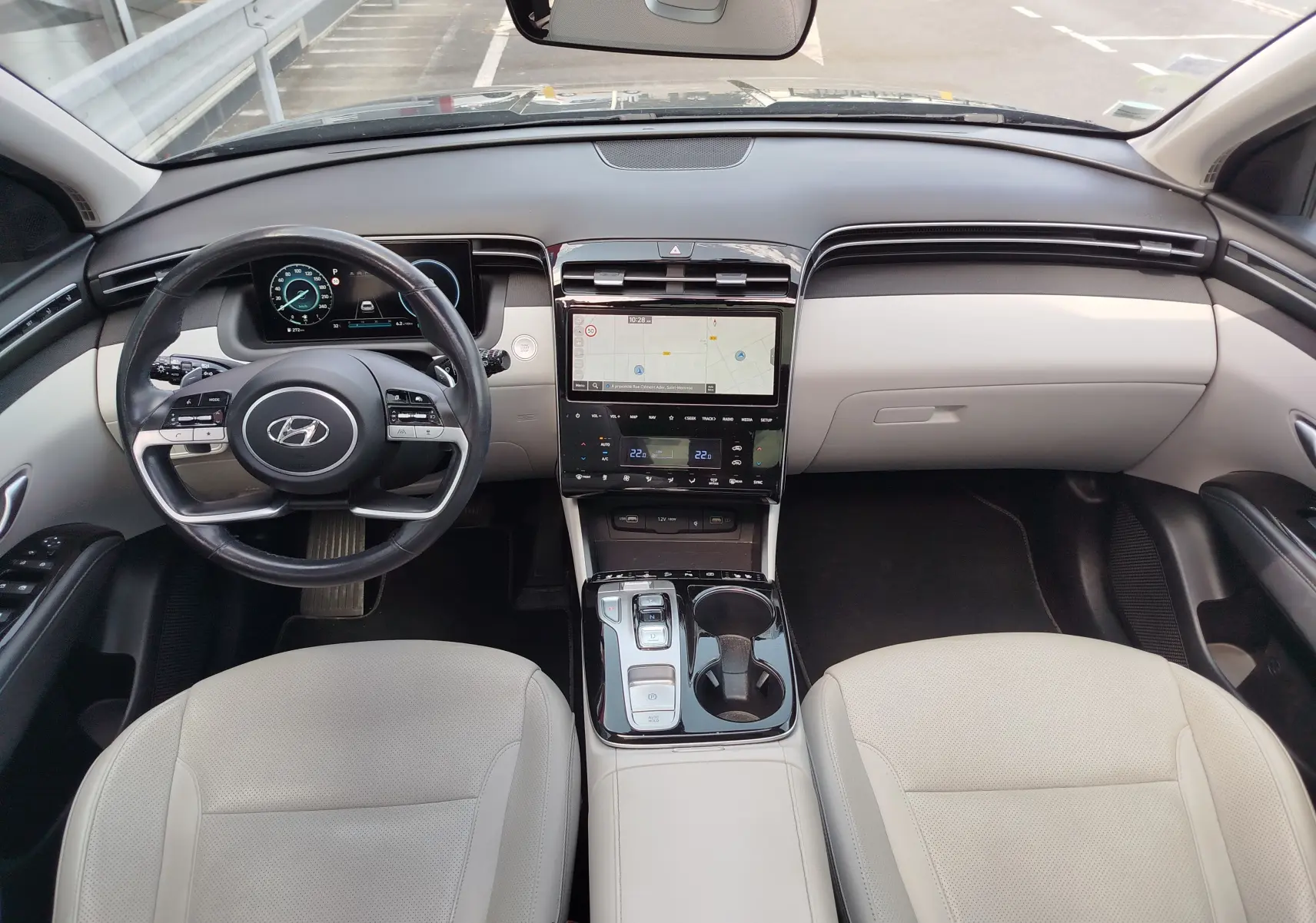 Vue intérieure frontale du Hyundai Tucson 2021, tableau de bord noir et beige avec écran tactile central et volant multifonction.