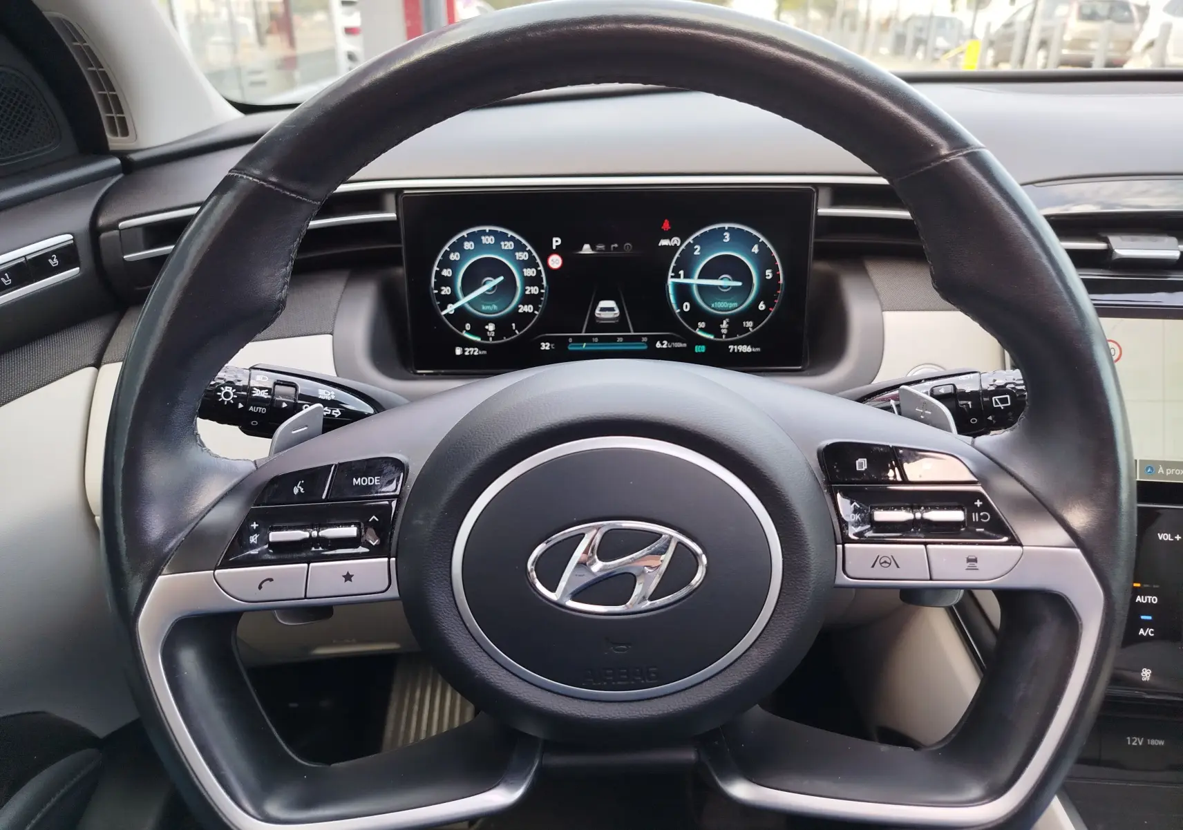 Vue rapprochée du volant cuir noir et du tableau de bord numérique du Hyundai Tucson 2021, intérieur beige et noir.