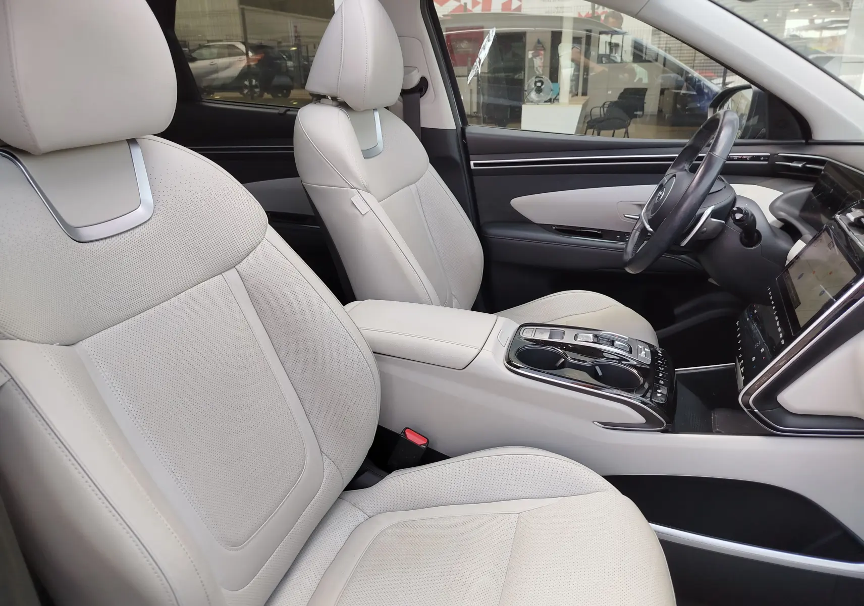 Vue intérieure côté conducteur du Hyundai Tucson 2021, sièges cuir beige clair et console centrale moderne.