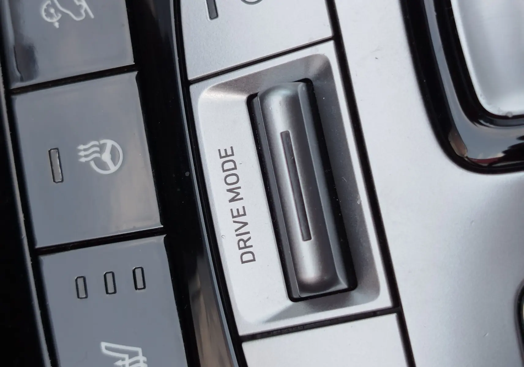 Gros plan sur les commandes argentées et noires du mode de conduite et des fonctions chauffantes dans le Hyundai Tucson 2021.