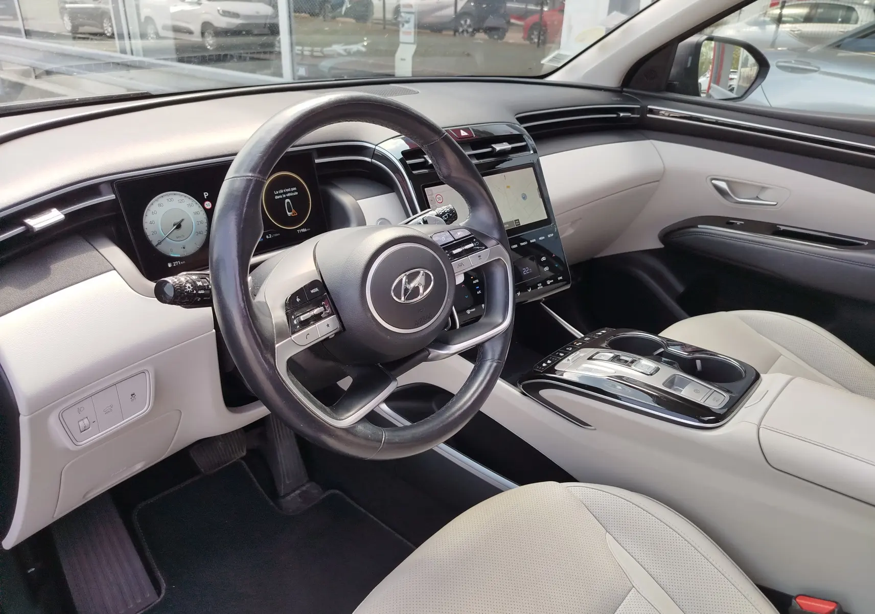 Vue intérieure côté conducteur du Hyundai Tucson 2021, tableau de bord moderne avec écran tactile et sellerie cuir beige.