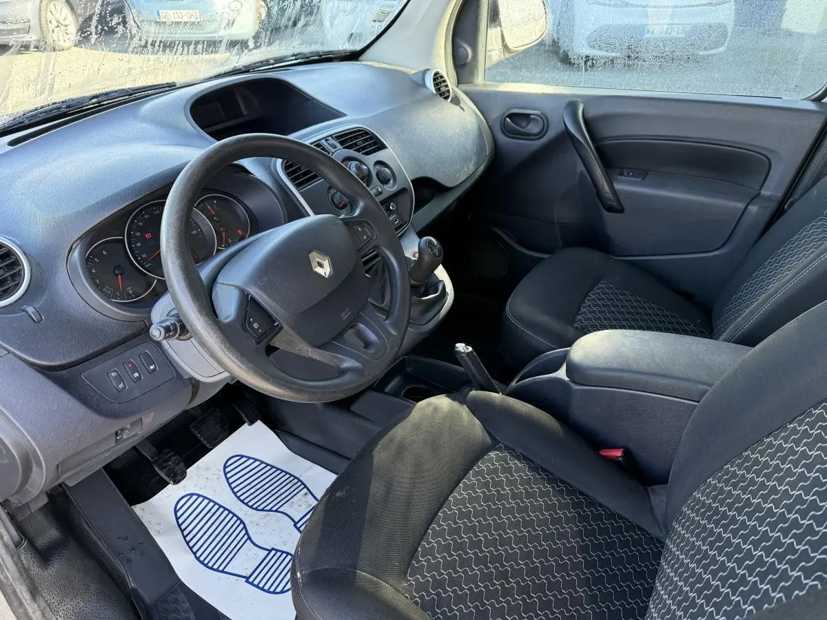 Intérieur avant du Renault Kangoo Express 2016, vue côté conducteur, sièges noirs et tableau de bord gris foncé.