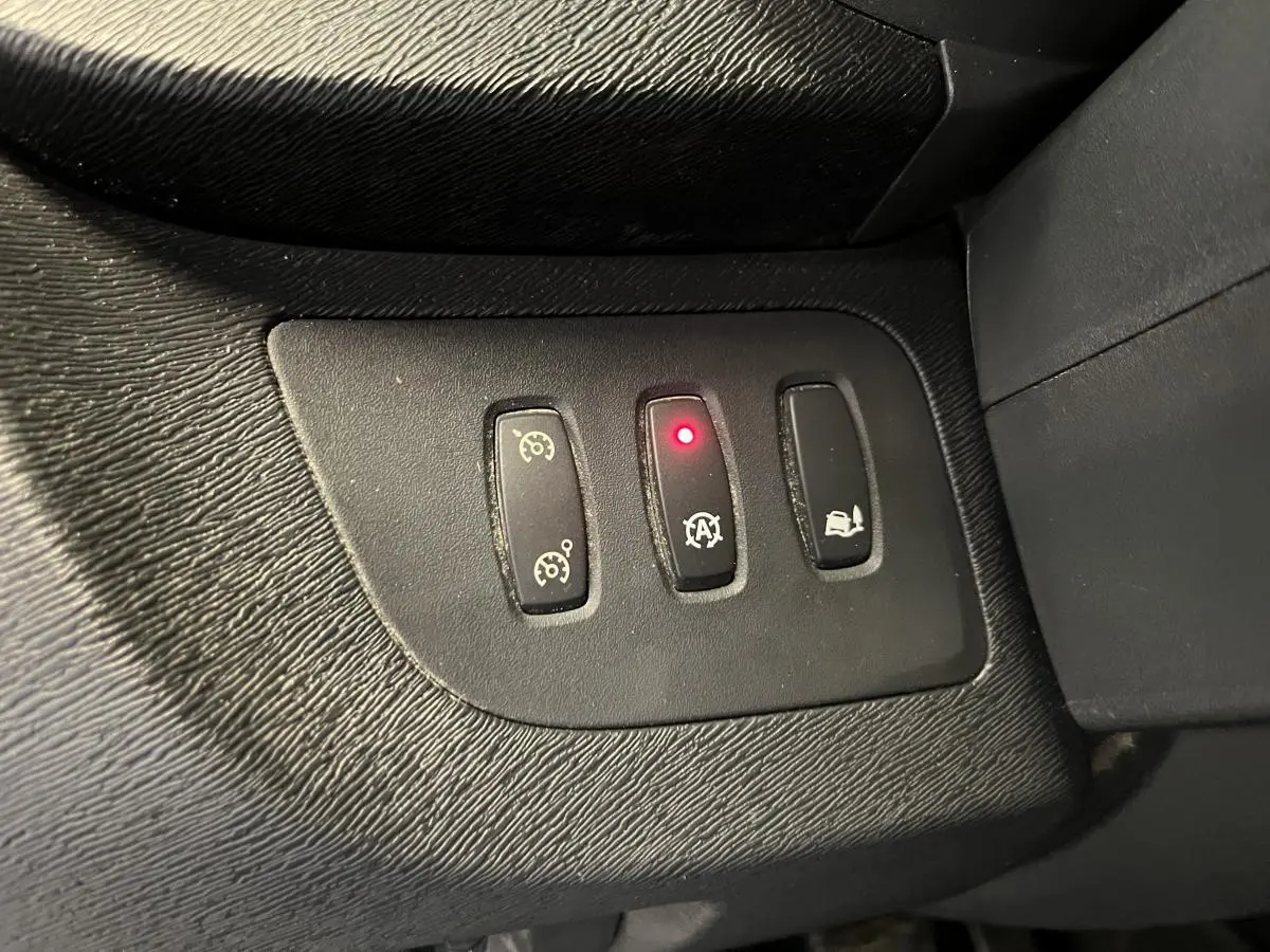 Gros plan sur les commandes du régulateur de vitesse et de l'arrêt automatique du moteur du Renault Kangoo Express gris foncé.