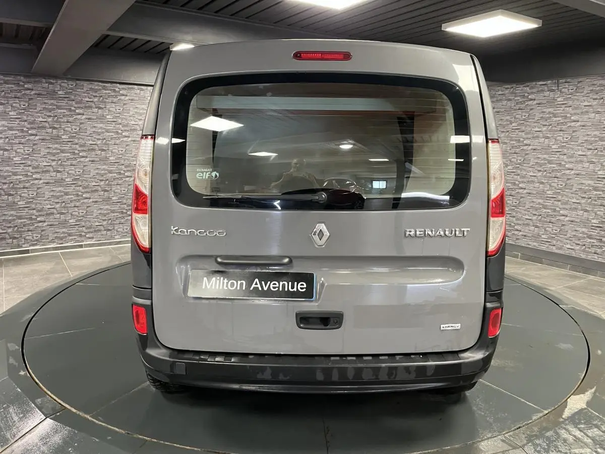 Vue arrière d'un Renault Kangoo Express gris foncé avec hayon vitré et pare-chocs noir grainé dans un showroom.
