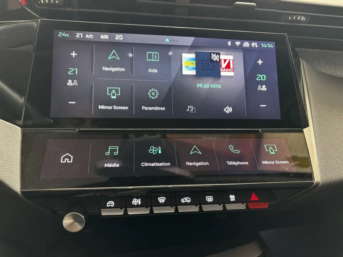Gros plan sur l'écran tactile central et la console de la Peugeot 308 PureTech 130 S&S Allure gris clair, affichage multimédia et climatisation.