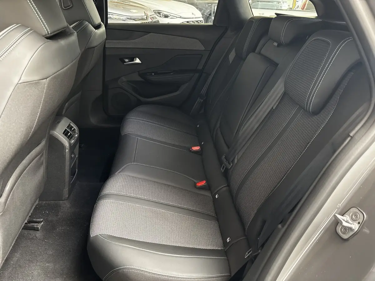 Vue intérieure côté droit montrant la banquette arrière noire et les finitions tissu et cuir de la Peugeot 308 gris clair.