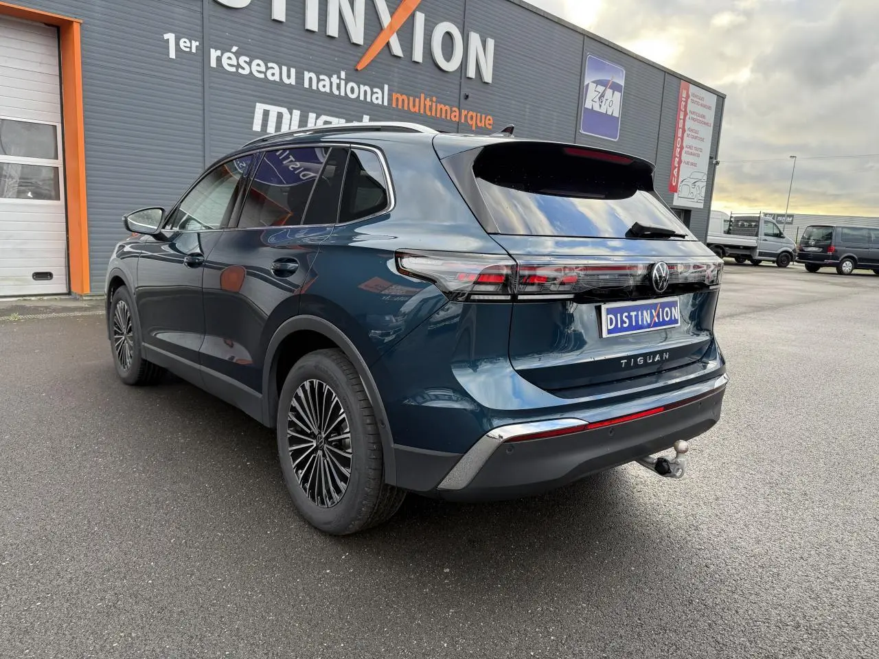 Vue 3/4 arrière droite du Volkswagen Tiguan 2024 bleu nuit métallisé avec crochet d'attelage et jantes alliage 18 pouces.