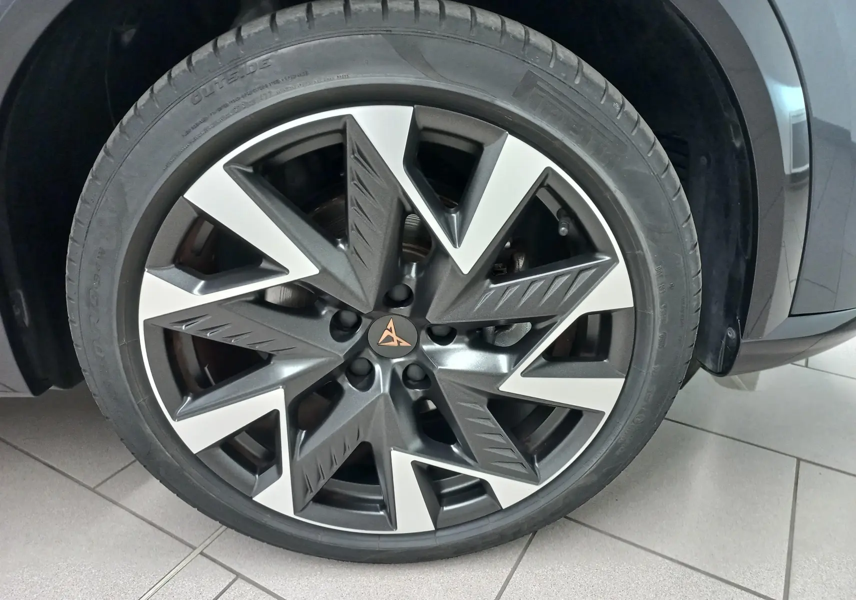 Gros plan sur la roue avant droite de la CUPRA Formentor gris magnétique, mettant en valeur la jante au design géométrique bicolore.