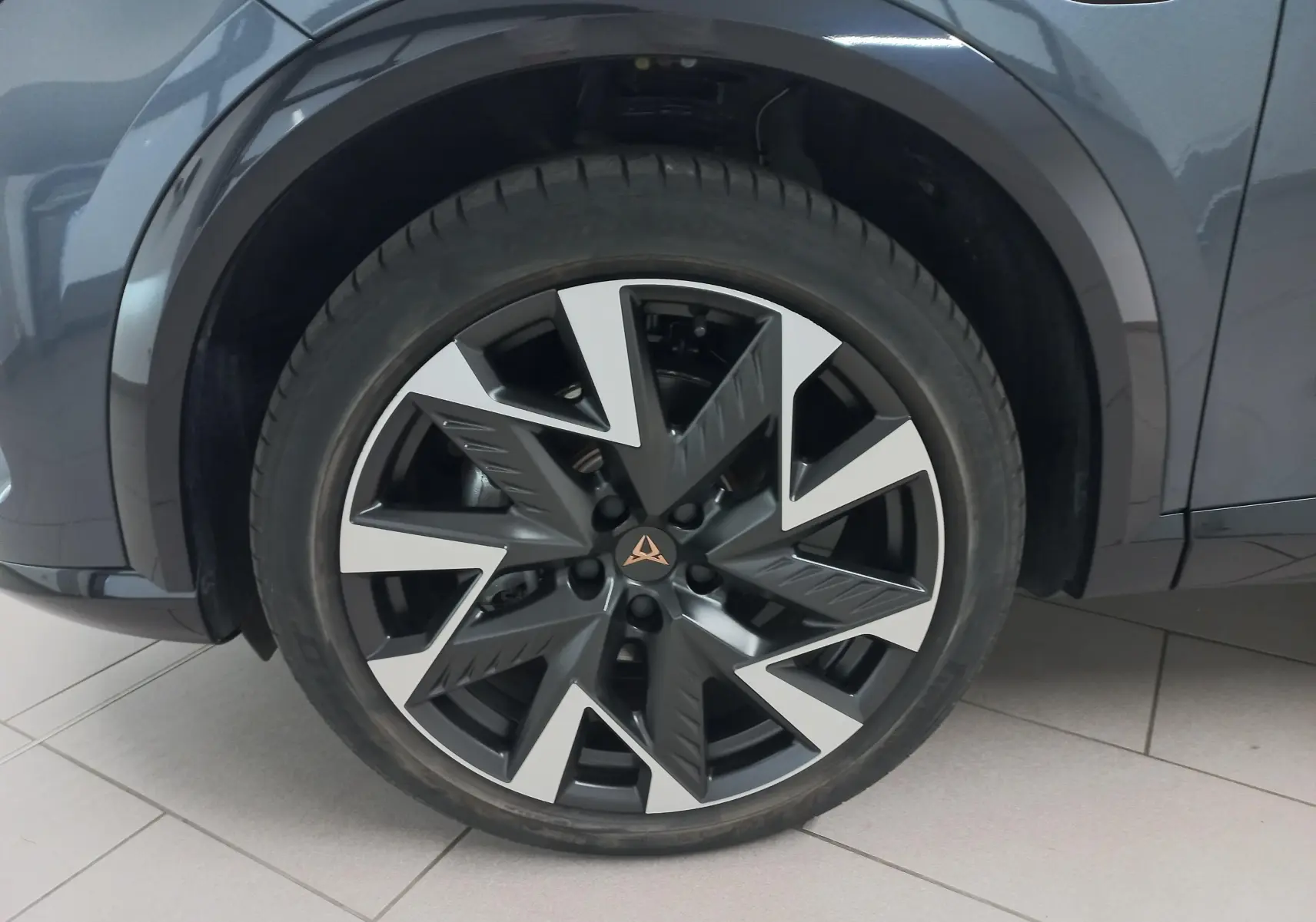Gros plan sur la roue avant droite du CUPRA Formentor gris magnétique, mettant en valeur la jante au design géométrique bicolore.