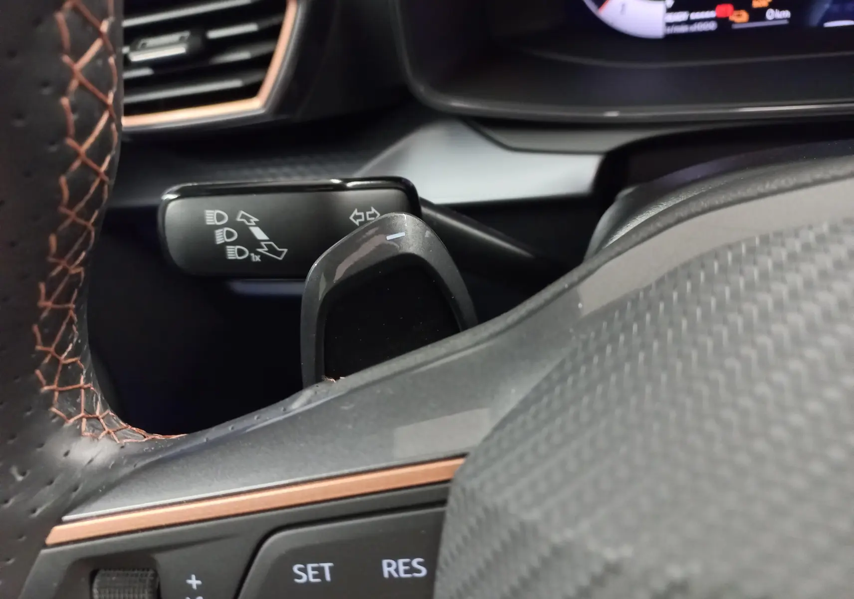 Détail du commodo des clignotants et du volant en cuir noir avec surpiqûres cuivrées dans l'habitacle du CUPRA Formentor hybride.