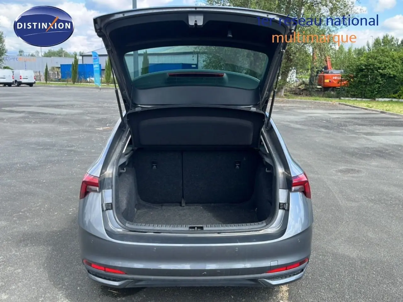 Vue arrière d'une Skoda Scala gris graphite métal 2025 avec coffre ouvert sur un parking extérieur.