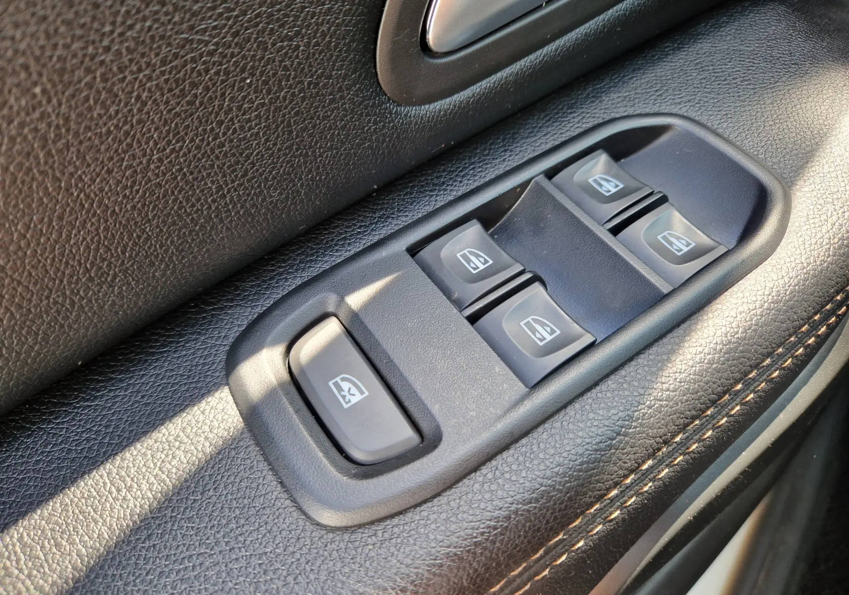 Gros plan sur les commandes électriques des vitres côté conducteur du Dacia Duster 2021, intérieur noir avec surpiqûres.