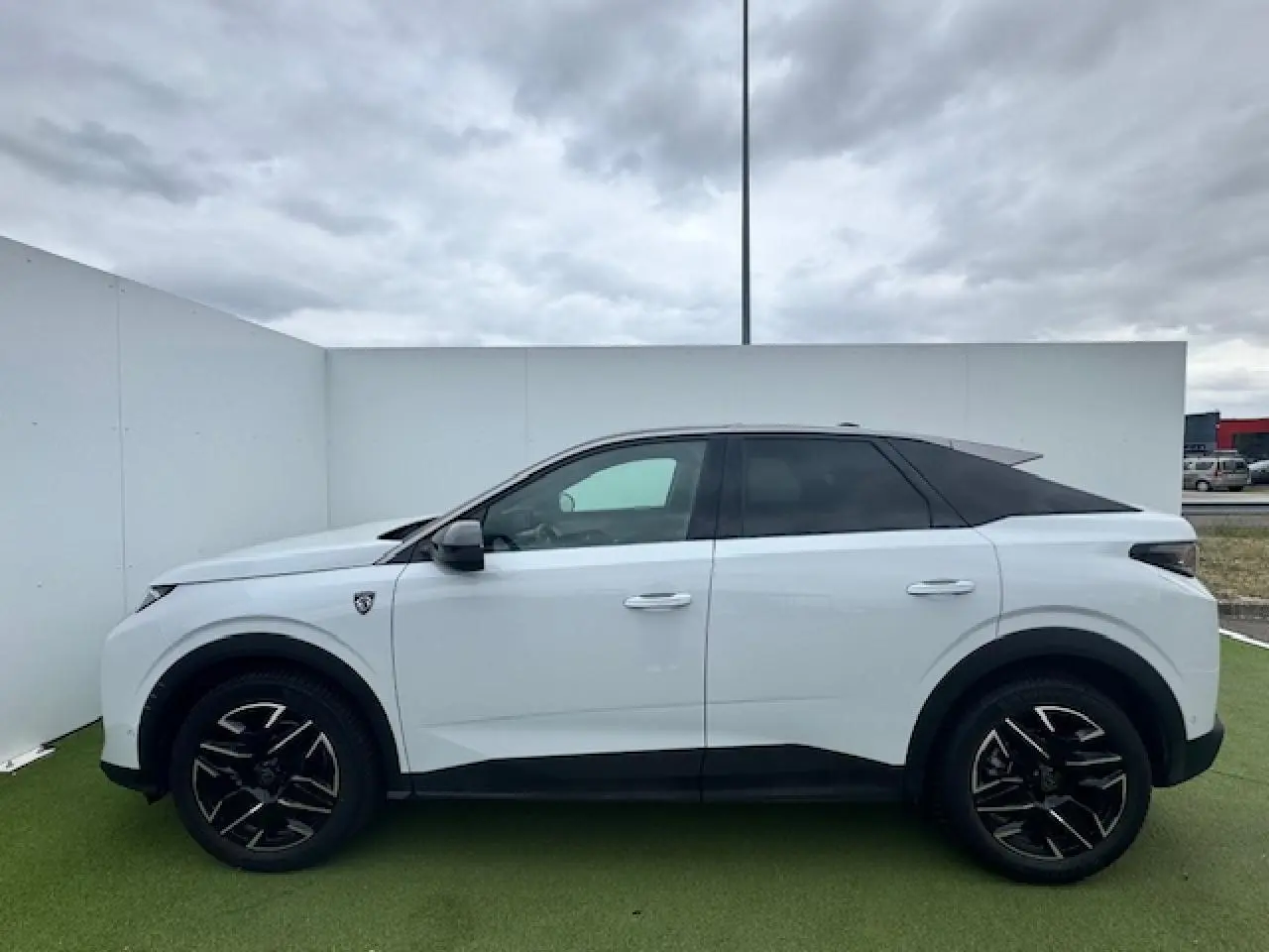 Profil droit du Peugeot 3008 blanc nacré avec toit noir, jantes alliage noires et écopes latérales noires.