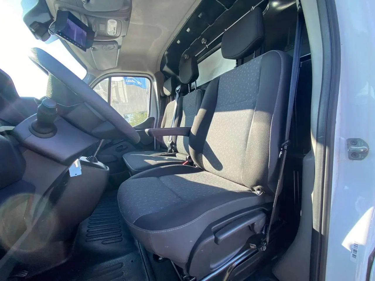 Vue intérieure côté conducteur du fourgon blanc Opel Movano 2021, montrant les sièges avant et le volant.