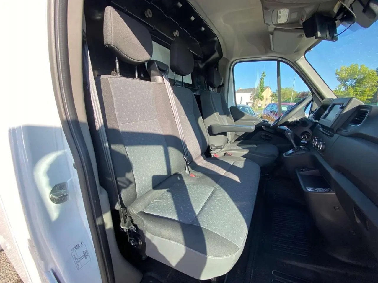 Vue intérieure côté conducteur de l'Opel Movano Fourgon blanc, montrant les sièges avant et le tableau de bord.