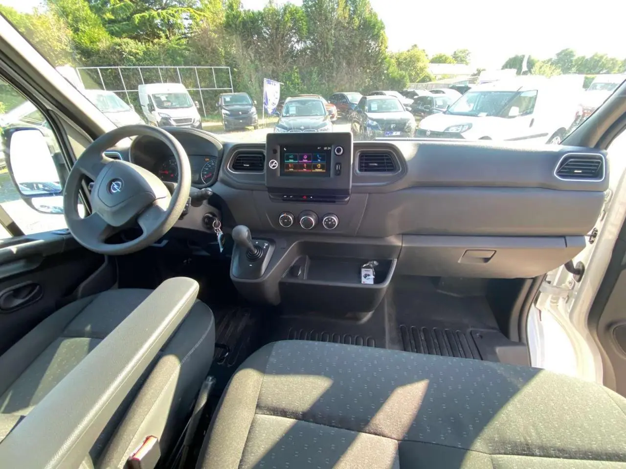 Vue intérieure avant de l'Opel Movano Fourgon blanc 2021, tableau de bord avec écran tactile et volant à gauche.