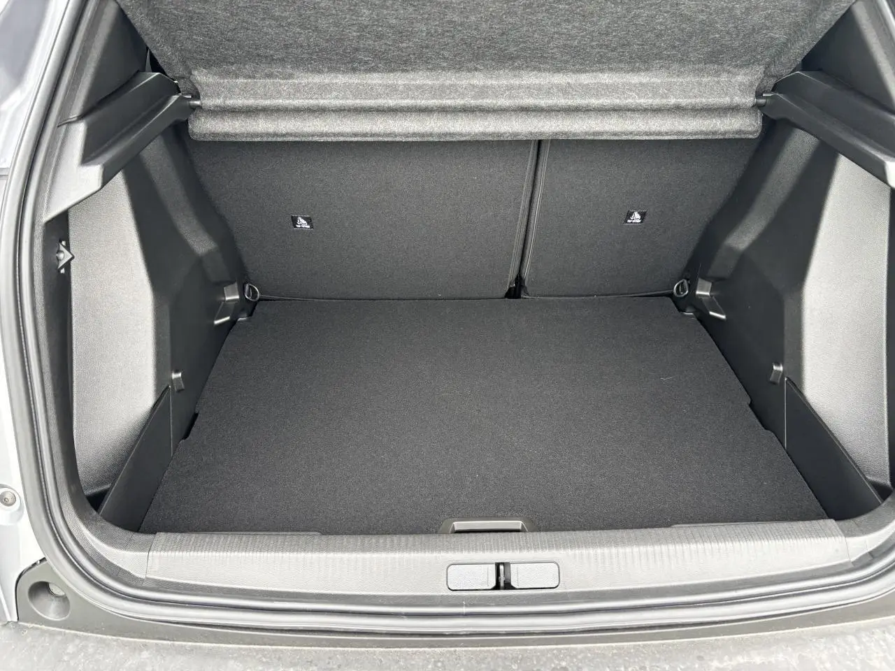 Coffre ouvert vu de l'arrière du Peugeot 2008 gris Artense avec intérieur noir et banquette rabattable.
