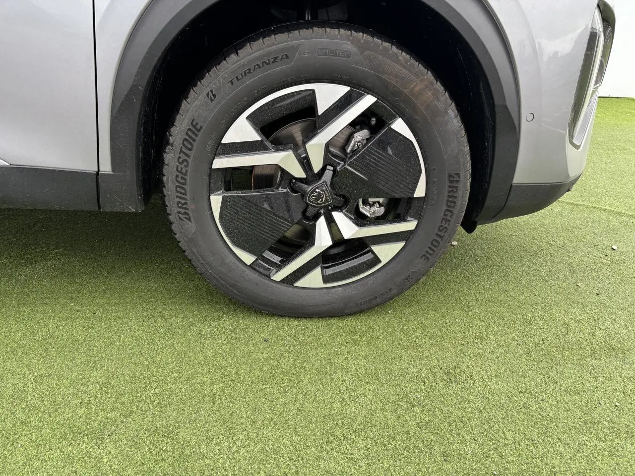 Gros plan sur la roue avant gauche du Peugeot 2008 gris Artense avec jante alliage 17'' bi-ton noir et argent.