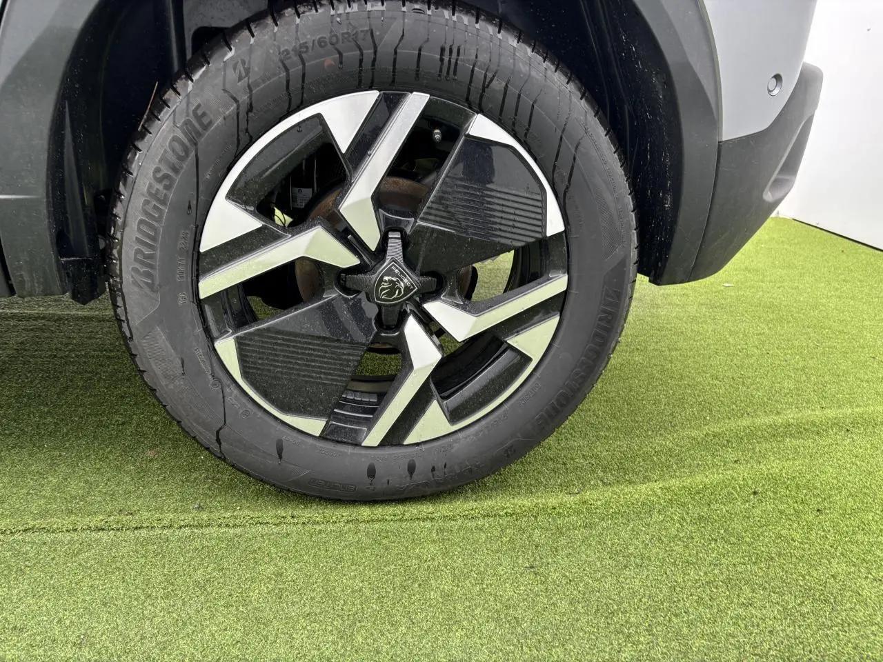 Gros plan sur la jante alliage 17'' bi-ton noir et argent du côté arrière droit d'un Peugeot 2008 gris Artense toit noir.