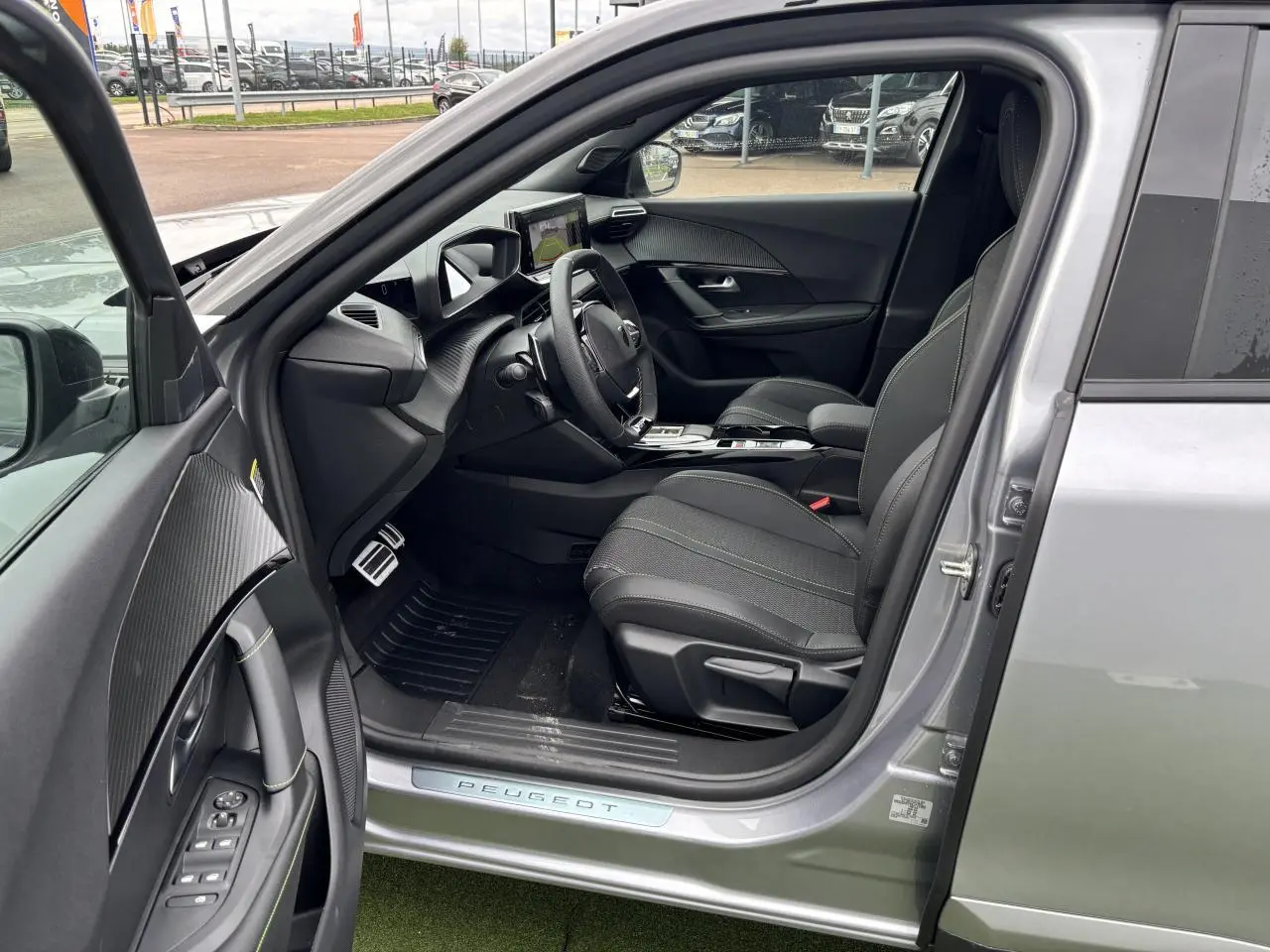 Intérieur côté conducteur du Peugeot 2008 gris Artense, montrant sièges tissu et volant compact cuir avec commandes.