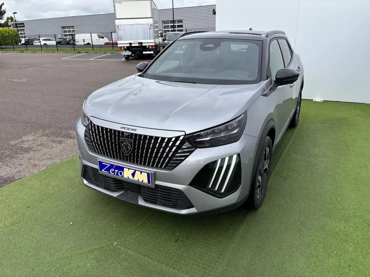 Peugeot 2008 II gris Artense toit noir en 3/4 avant droit, calandre noire verticale et feux LED griffés visibles