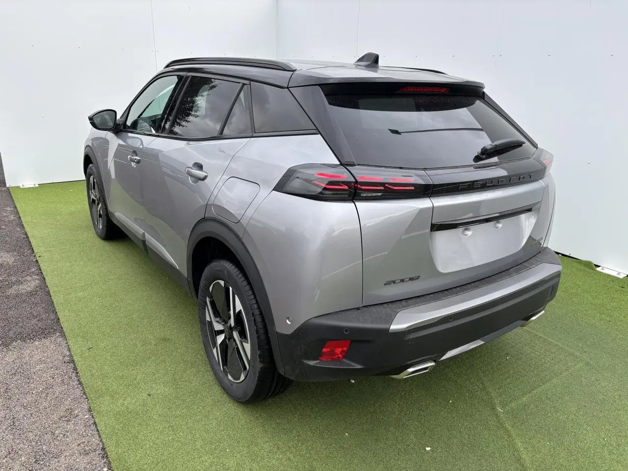 Vue 3/4 arrière droite du Peugeot 2008 gris Artense avec toit noir et feux arrière à LED 3 griffes.