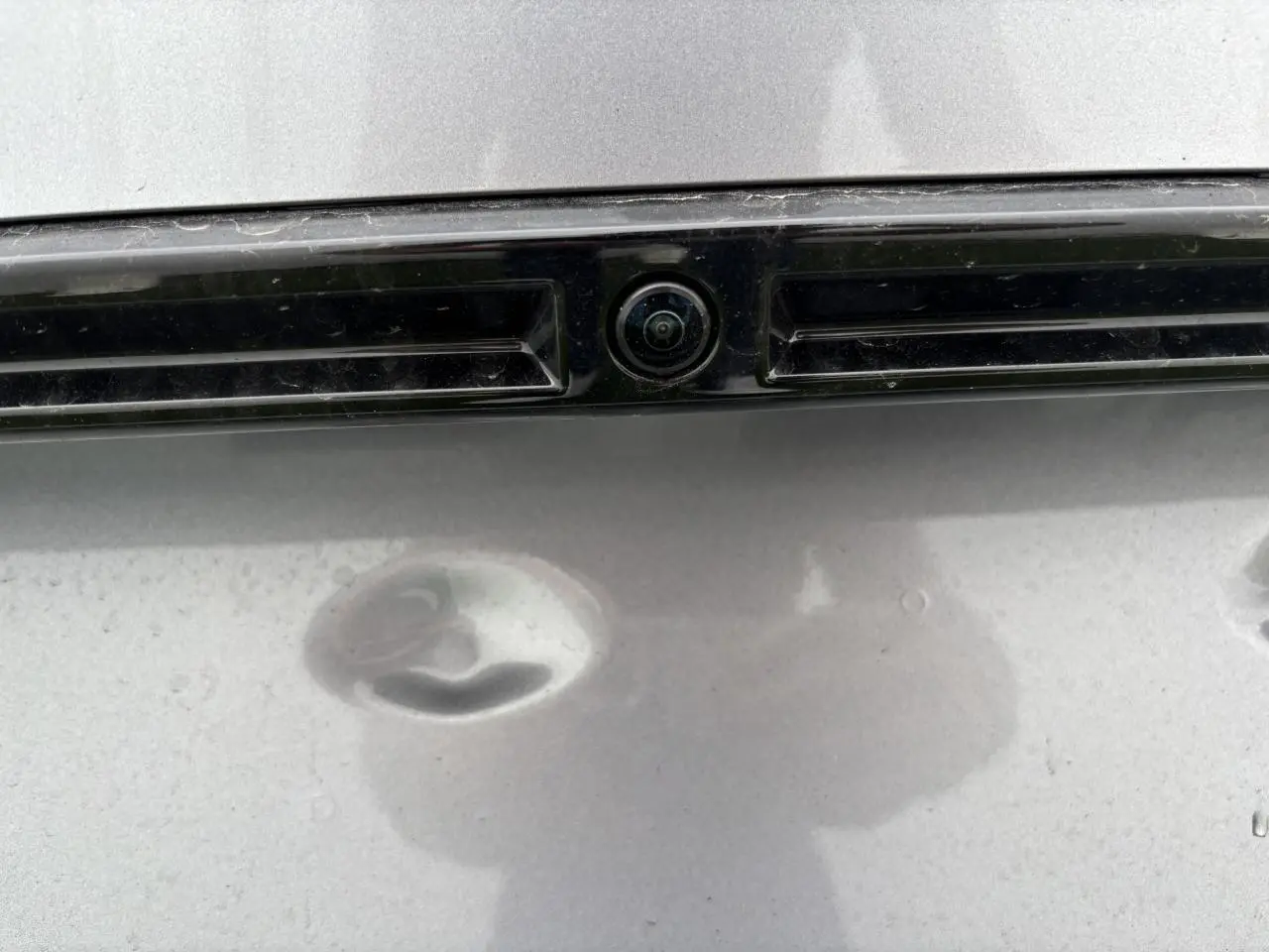 Gros plan sur la caméra 360° arrière intégrée à la malle du Peugeot 2008 gris Artense avec toit noir.