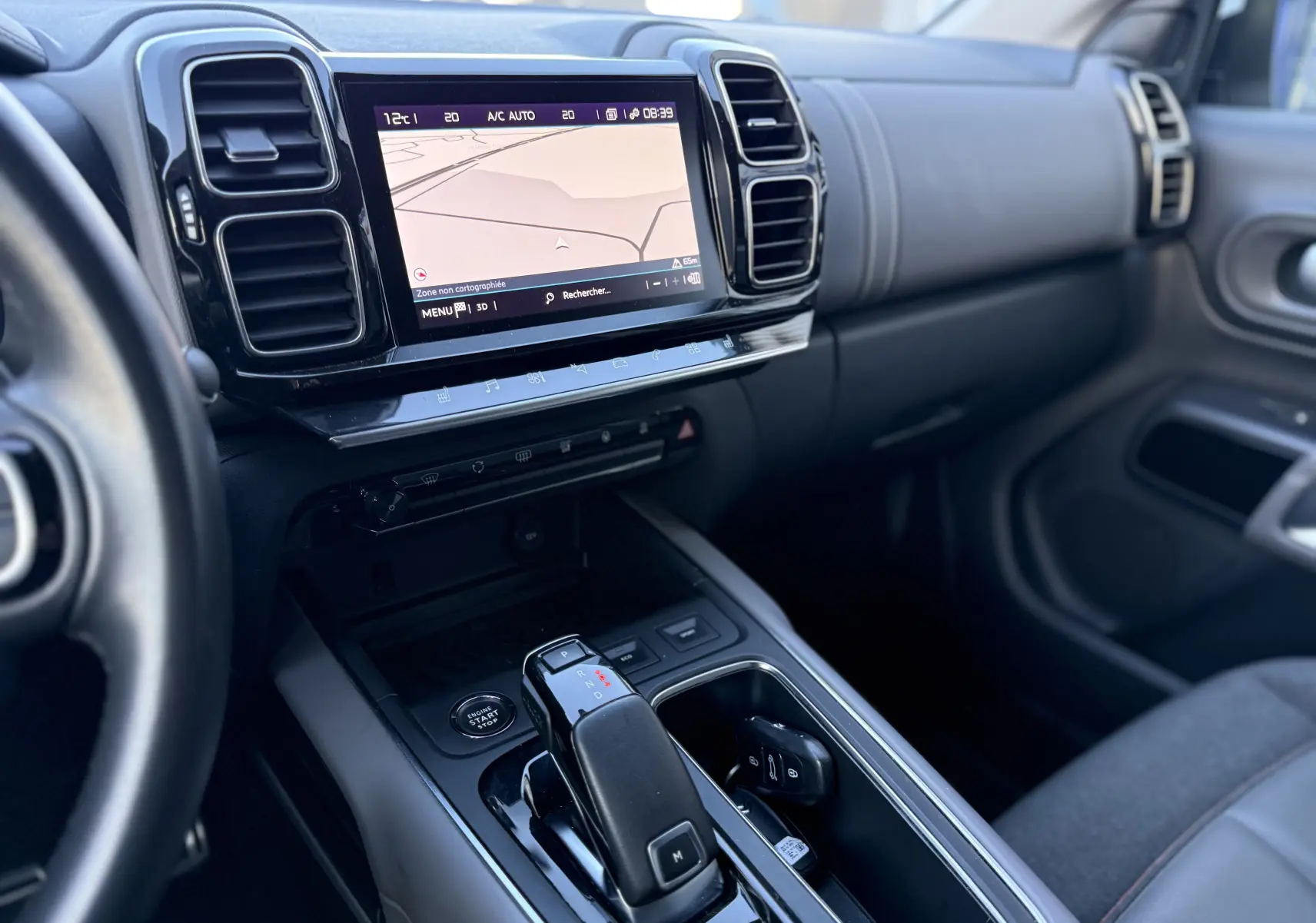 Vue intérieure côté conducteur du tableau de bord et console centrale du Citroën C5 Aircross blanc nacré avec écran tactile et boîte auto.