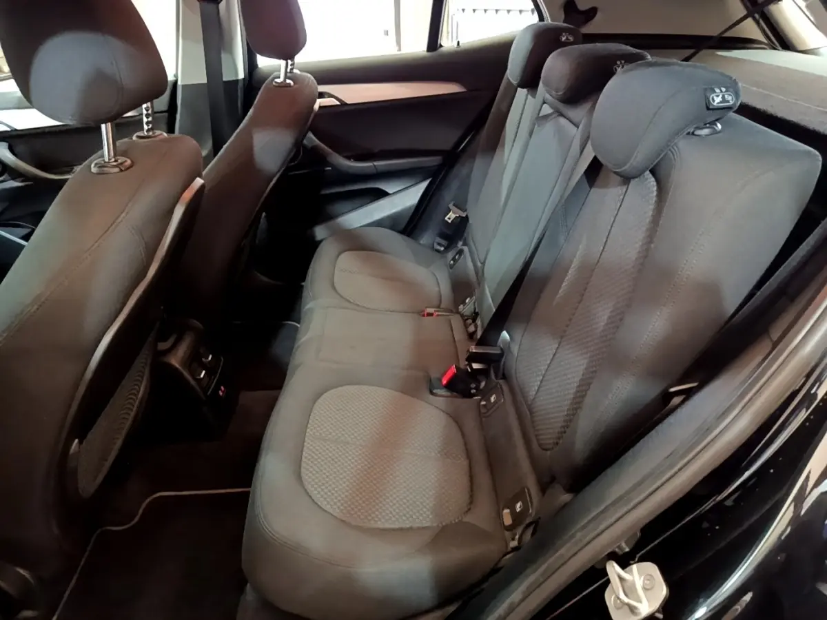 Vue intérieure arrière côté droit du BMW X2 sDrive18i Lounge 2023 noir, montrant la banquette et les appuie-têtes enfant.