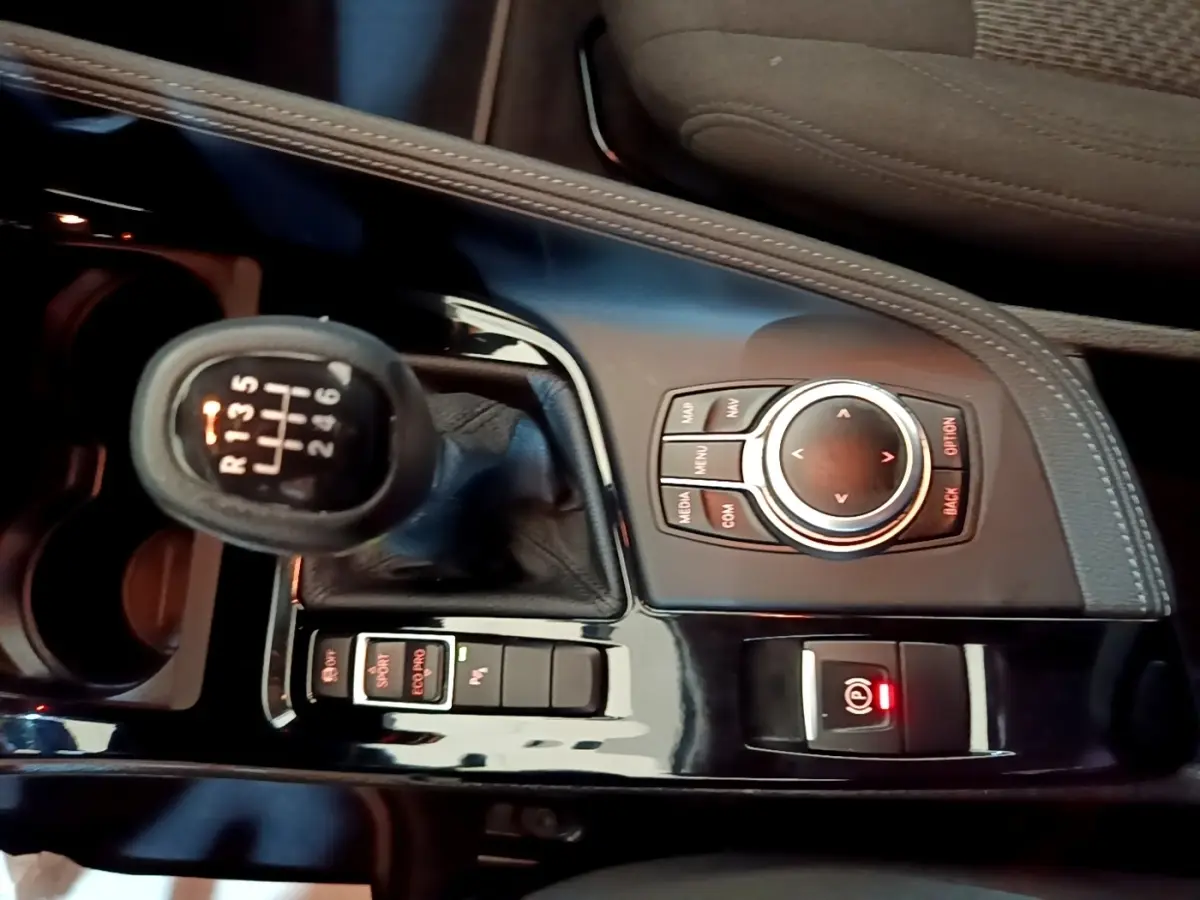 Vue rapprochée de la console centrale noire du BMW X2 sDrive18i 2023 avec levier de vitesses manuel et molette de contrôle.