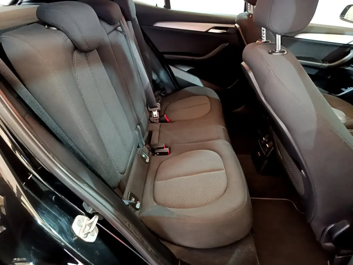 Vue intérieure côté gauche des sièges arrière noirs en tissu du BMW X2 sDrive18i Lounge 2023 avec port USB et aérateurs.