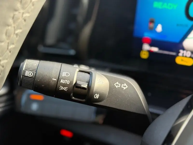 Gros plan sur la commande des feux et clignotants à gauche du volant dans l’habitacle du Renault Austral blanc nacré 2025.