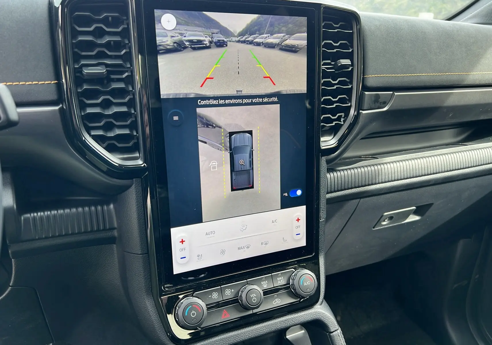Vue intérieure du tableau de bord noir du Ford Ranger 2026 avec écran tactile central affichant caméra 360° et commandes climatisation.