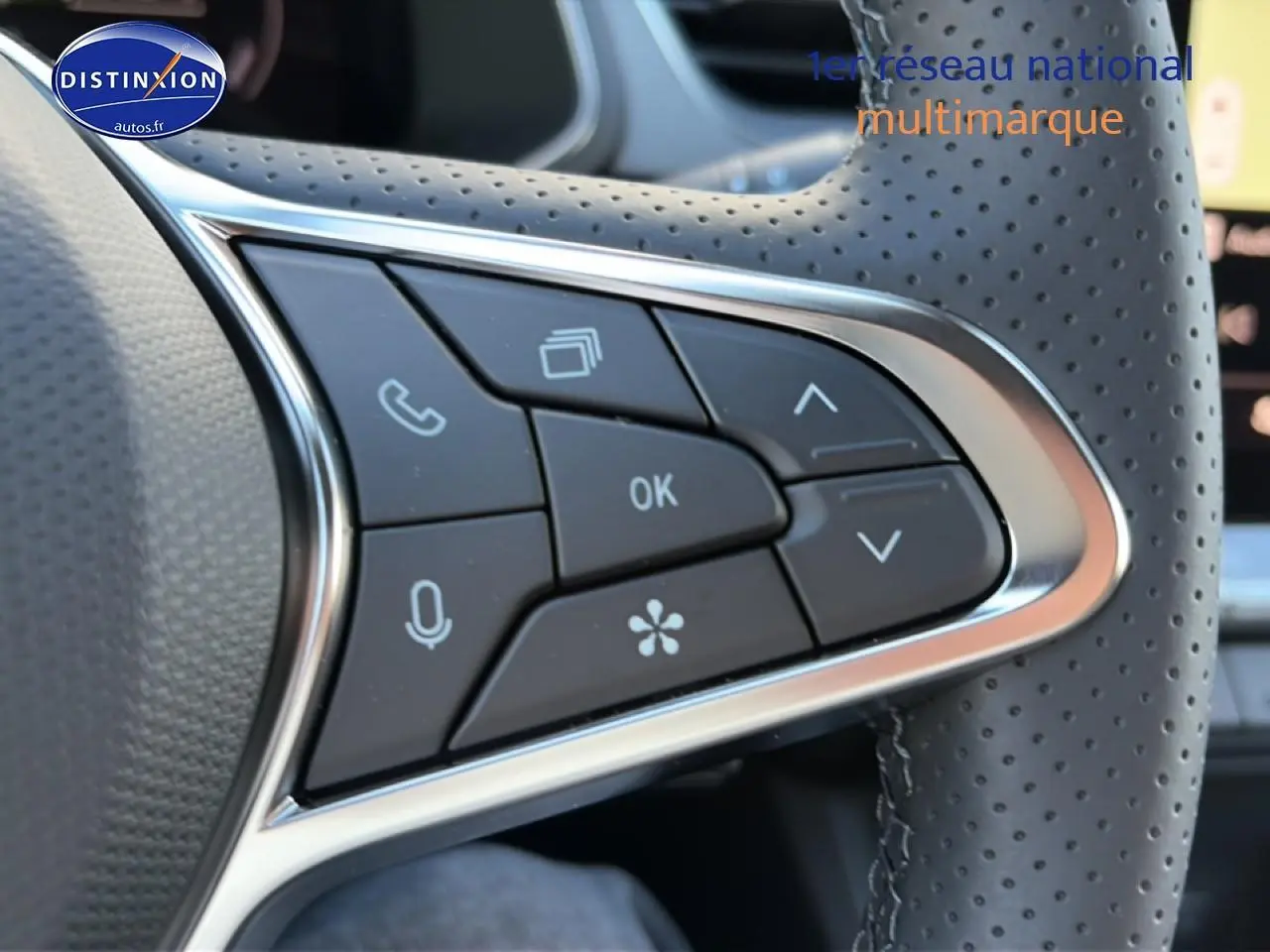 Gros plan sur les commandes multifonctions au volant en cuir perforé du Renault Captur 2026 bleu iron toit noir.