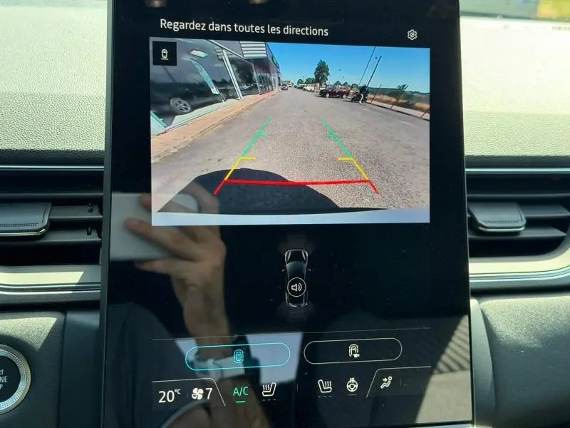 Écran tactile intérieur montrant la caméra de recul du Renault Captur blanc nacré, vue arrière du véhicule en stationnement.