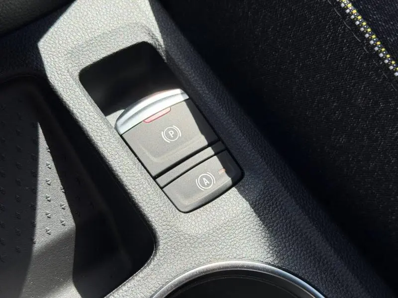Gros plan sur les commandes de frein à main électronique et arrêt auto du moteur du Renault Captur blanc nacré.