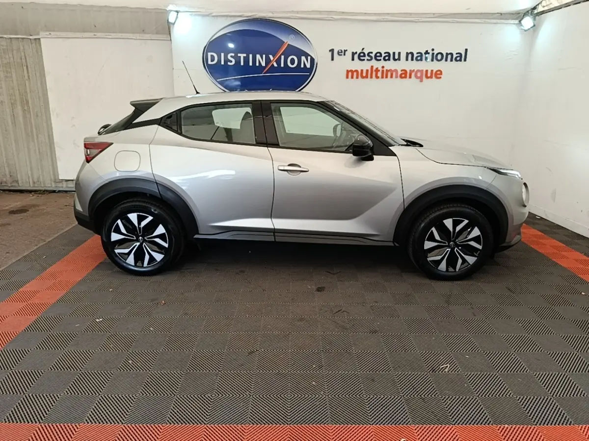 Profil côté gauche du Nissan Juke Business Edition gris clair 2023, avec jantes noires et détails noirs contrastants.