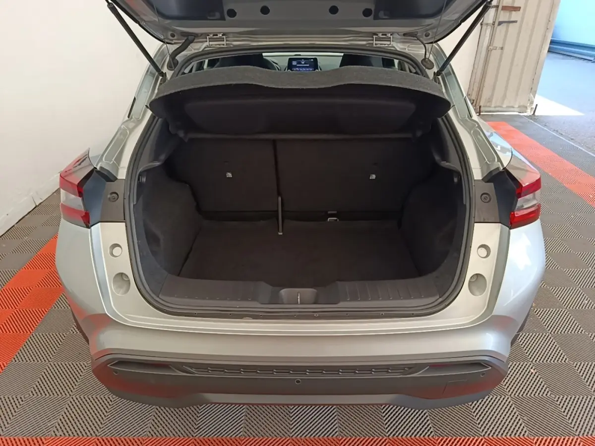 Vue arrière du coffre ouvert d'un Nissan Juke gris clair 2023, montrant l'espace de chargement intérieur.