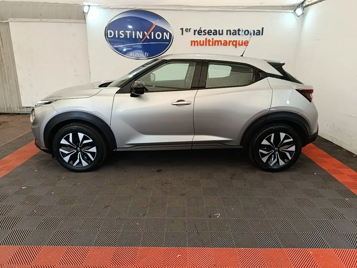 Vue latérale droite du Nissan Juke gris clair 2023 avec jantes bicolores et toit noir contrastant.