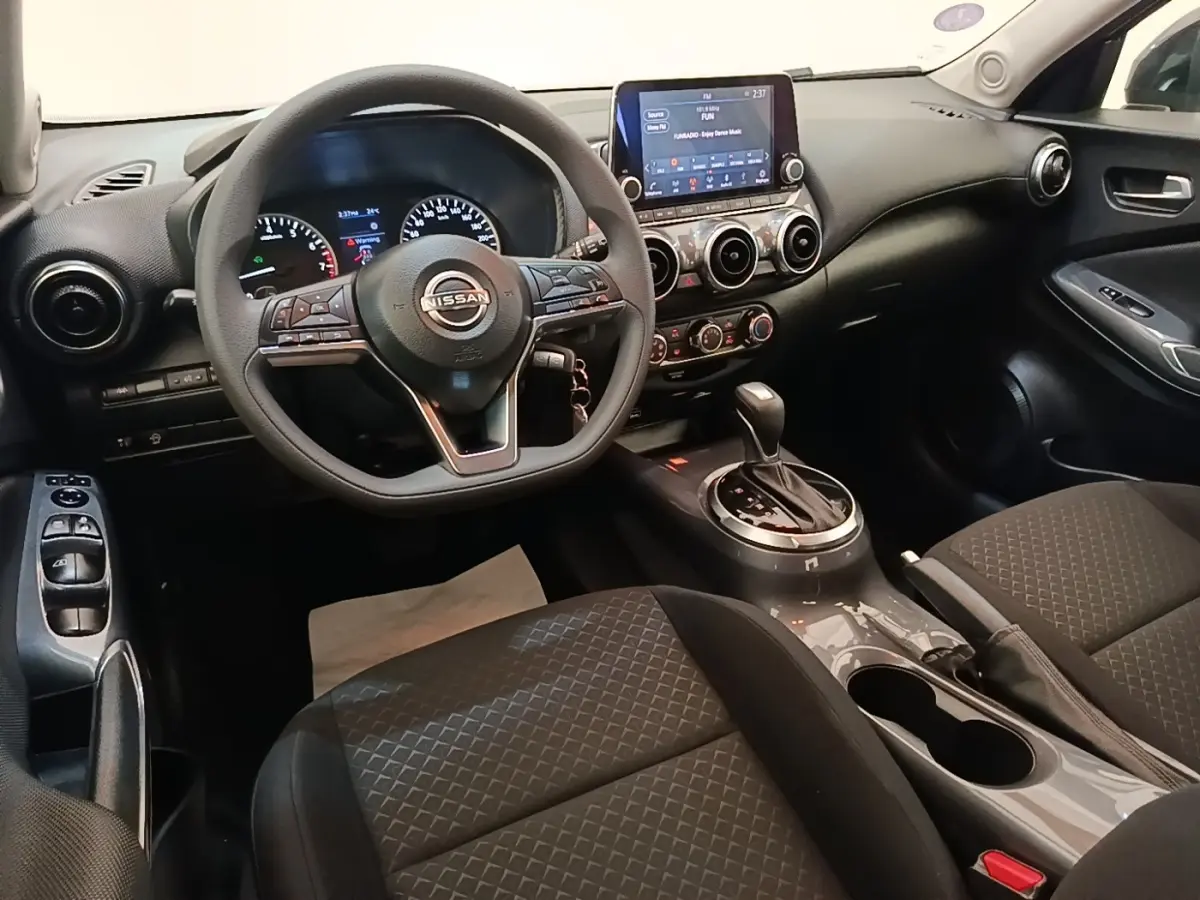 Intérieur du Nissan Juke 2023, vue avant centrée sur le volant multifonctions et la console avec écran tactile.