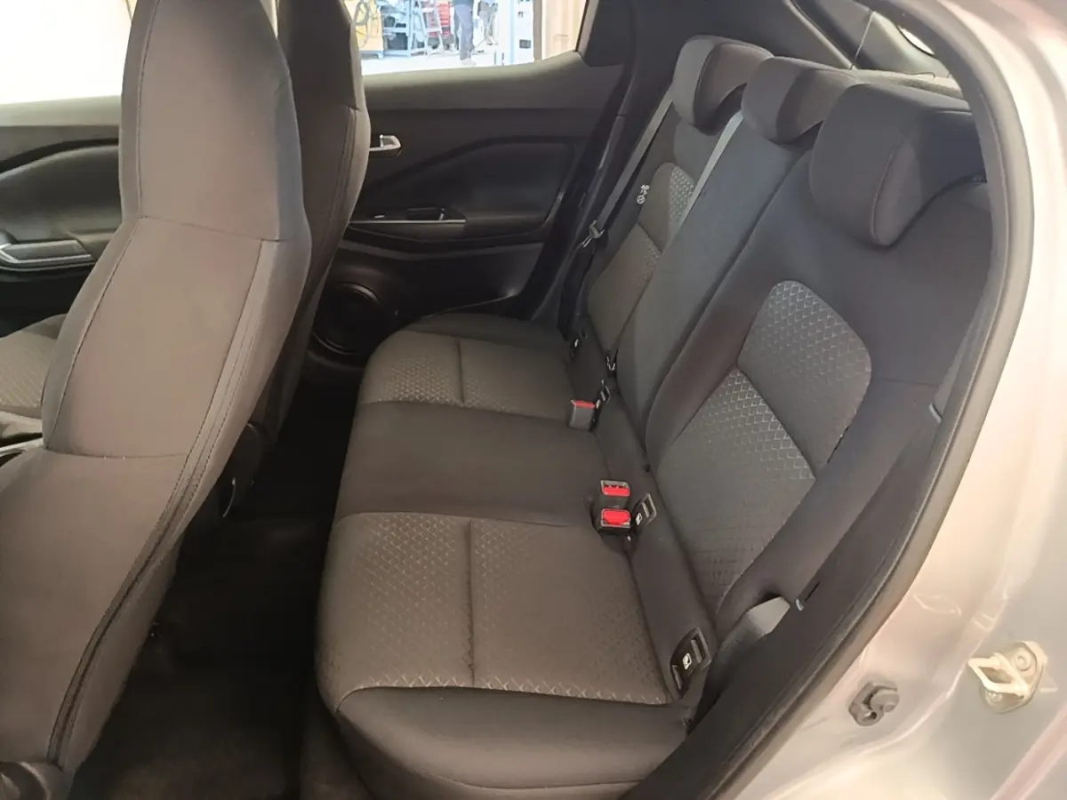 Vue intérieure côté droit sur la banquette arrière noire du Nissan Juke gris clair 2023, avec ceintures et appuie-têtes visibles.