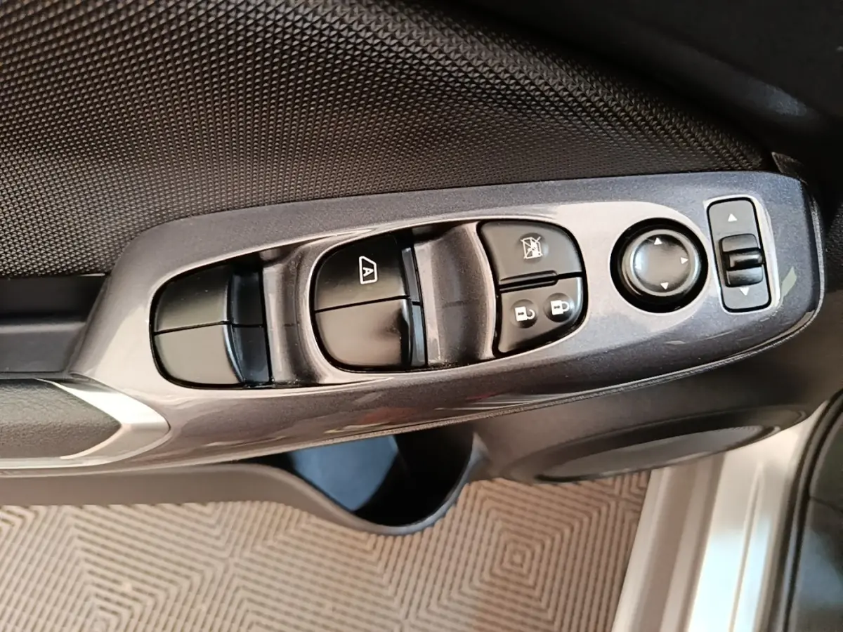 Gros plan sur les commandes de lève-vitres et rétroviseurs côté conducteur du Nissan Juke gris clair 2023.