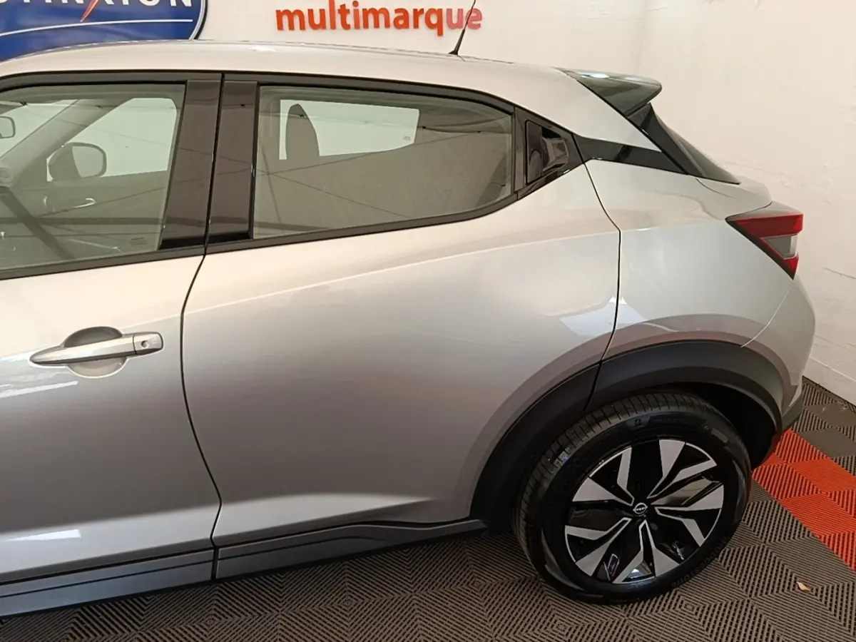 Vue latérale côté gauche du Nissan Juke gris clair 2023 avec jantes alliage et poignées de porte ton caisse.