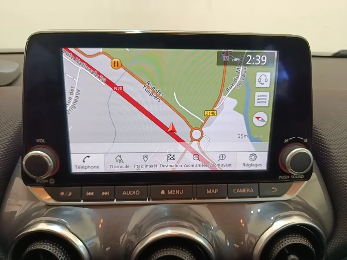 Écran tactile central du Nissan Juke 2023 affichant la navigation 3D avec commandes audio et climatisation en dessous.