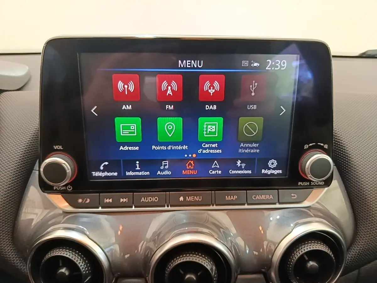 Écran tactile central 8 pouces du Nissan Juke gris clair 2023, avec commandes audio et navigation visibles.