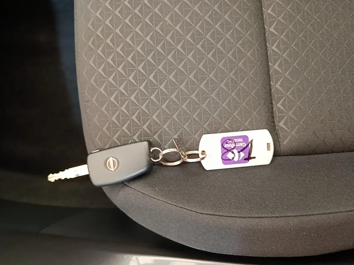 Clé Nissan posée sur un siège tissu gris foncé avec motif géométrique à l'intérieur du véhicule.
