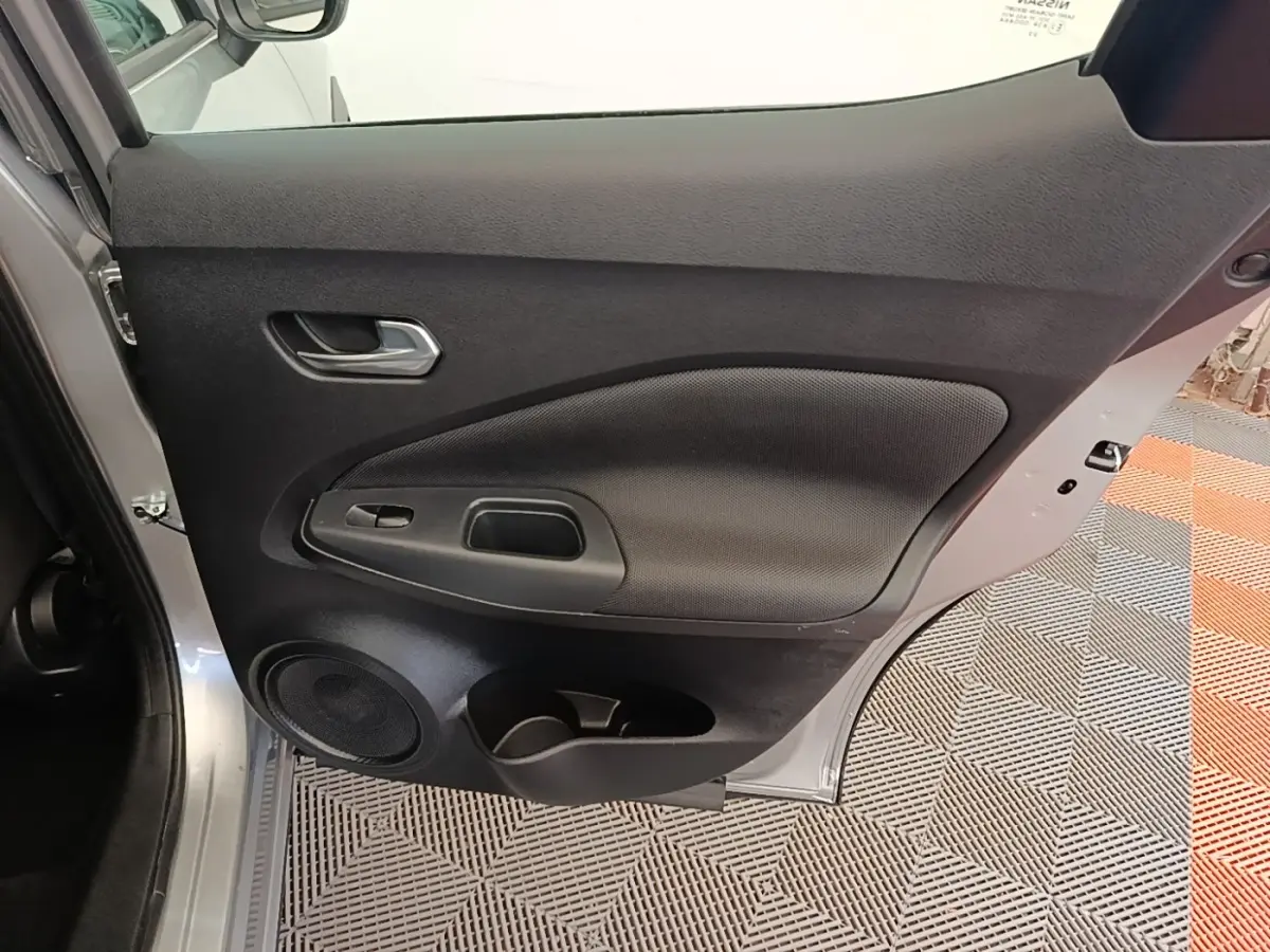 Vue intérieure de la porte arrière gauche gris clair du Nissan Juke 2023 avec haut-parleur et poignée intégrée.