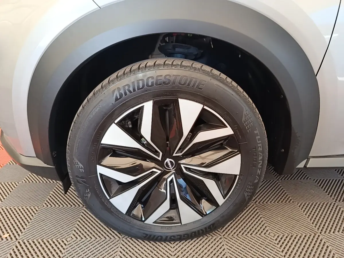 Gros plan sur la roue avant droite du Nissan Juke gris clair, jante alliage noir et argent au design moderne.