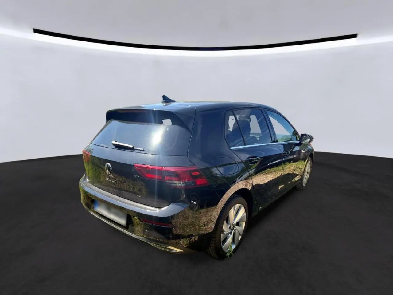 Vue 3/4 arrière droite d'une Volkswagen Golf VIII noire avec feux arrière LED et jantes alliage 17 pouces.