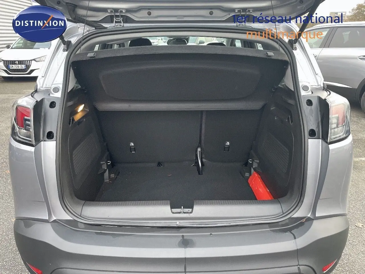 Coffre ouvert vu de l'arrière d'un Opel Crossland gris minéral métal, montrant l'espace de chargement vide.